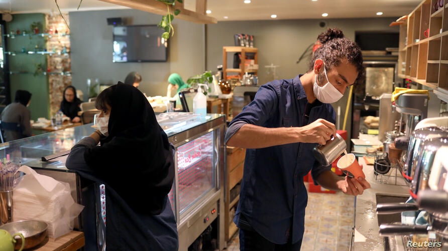 A worker wearing a protective face mask prepares a coffee at a coffee shop, following the outbreak of the coronavirus disease (COVID-19), in Tehran, I -  by mohsen dehbashi